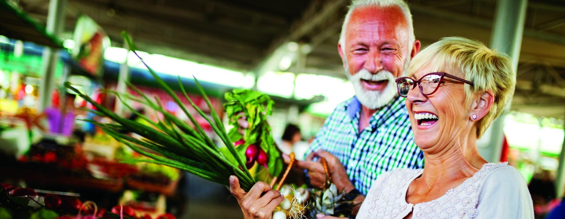 a man and woman holding a basket of vegetables